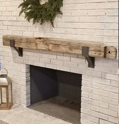 a white brick fireplace with a wooden mantle and wreath on the mantel above it