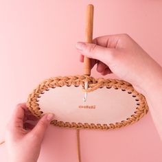 a person holding a piece of wood with a string attached to it and another hand