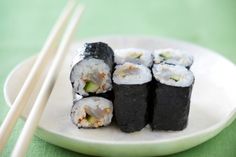 sushi on a white plate with chopsticks next to it and a green tablecloth