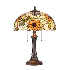 a table lamp with a sunflower design on the base and a glass shade over it