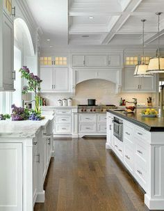 a large kitchen with white cabinets and black counter tops, along with an island in the middle