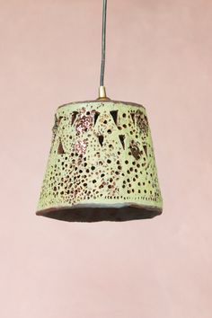 a green light fixture hanging from a pink wall