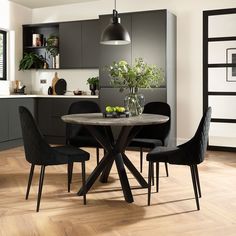 a dining room table with black chairs and a vase filled with flowers on top of it