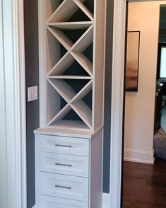 a tall white bookcase sitting in the corner of a room