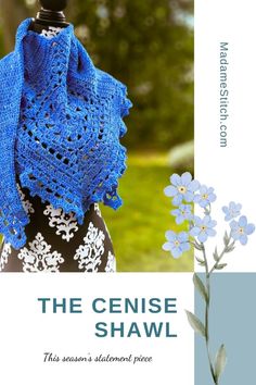 the crochet shawl is on display in front of a blue background with white flowers