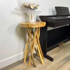 a vase with flowers sitting on a stool next to a piano