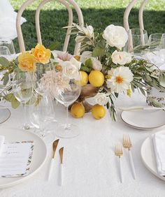 the table is set with white and yellow flowers