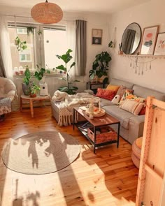 a living room filled with furniture and lots of plants in the window sills