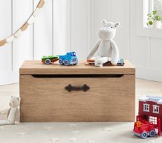 a teddy bear sitting on top of a wooden box next to toy cars and trucks