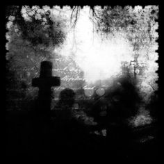 a black and white photo of a cemetery with a cross in the foreground, surrounded by tombstones