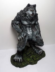 a statue of a wolf sitting on top of a mossy rock with claws spread out