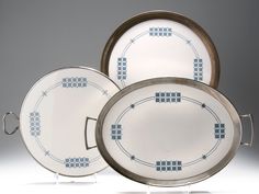 three white and blue plates sitting next to each other on top of a gray surface