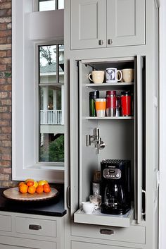 a coffee cabinet in the kitchen with oranges on it and an open door to another room