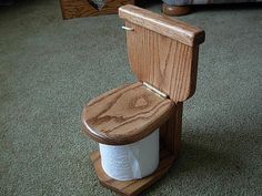 a wooden toilet sitting on top of a green carpeted floor next to a bed