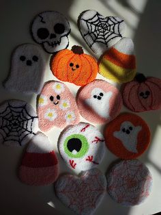 knitted pumpkins and ghost faces are arranged on a white surface with shadows from the window