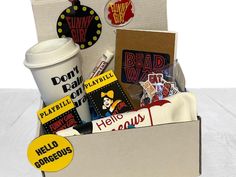 a box filled with assorted items sitting on top of a white table next to a cup