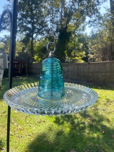 a glass bird feeder hanging from a metal pole