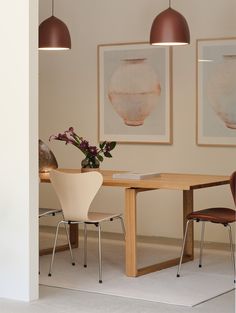 a dining room table with two chairs and a vase on the table next to it