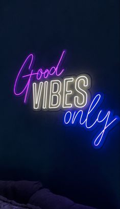 a neon sign that says good vibes only on the side of a dark room