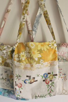 three purses hanging on a wall with flowers and lace trimming the bottom one