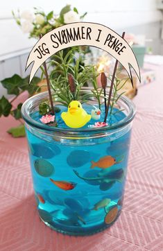 a vase filled with blue water and small yellow rubber duck