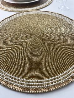 the table is set with gold and white placemats, silver plates, and wine glasses