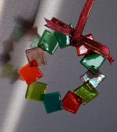 a christmas ornament made out of glass blocks with a red ribbon hanging from it