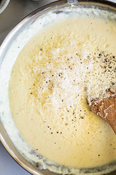 a wooden spoon in a pan filled with cheese