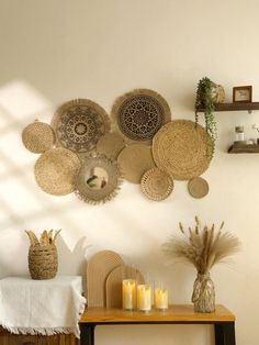 a table with candles and baskets on it next to a wall mounted wicker art piece