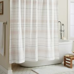 a white shower curtain in a bathroom next to a toilet and bathtub with a rug on the floor