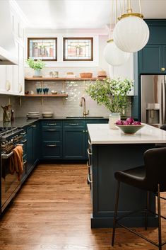 a kitchen with blue cabinets and white counter tops, two hanging lights above the island