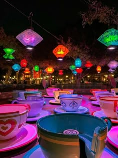 many cups and saucers are lit up with colorful lights