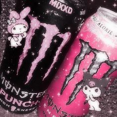 two monster energy drink cans sitting next to each other on the ground with pink and black designs