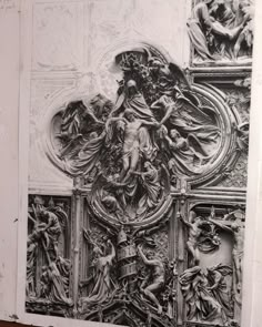 an intricately carved panel with angels and other figures on the wall, in black and white