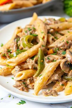 pasta with mushrooms and green peppers on a white plate