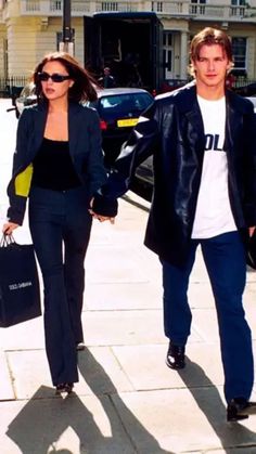 a man and woman are walking down the street holding hands with each other while carrying shopping bags