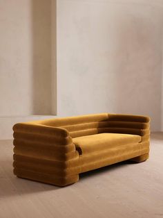 a yellow couch sitting on top of a hard wood floor next to a white wall