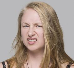 a woman with long blonde hair is looking at the camera and has an angry look on her face