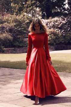 a woman in a red dress is walking down the street with her hands on her hips