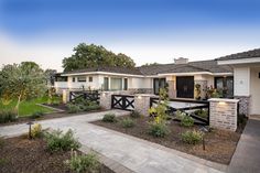 the front yard of a house with landscaping around it and trees in the background at dusk