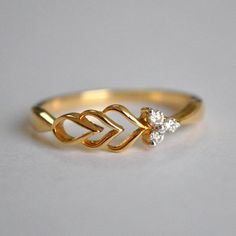 a gold ring with an arrow and two diamonds on it, sitting on a white surface