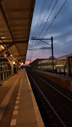 an empty train station at dusk with the lights on