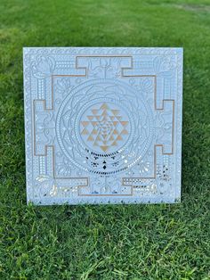 a white and gold box sitting on top of a green grass covered field with an intricate design