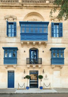 an old building with blue shutters on the windows and balconies in front