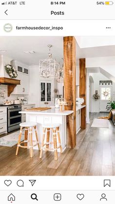 an open concept kitchen and living room with wood flooring, white cabinets and bar stools