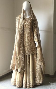 a mannequin dressed in an elaborate gold gown and shawl is displayed on a white pedestal