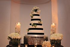 a black and white wedding cake surrounded by candles