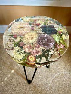 a glass table with flowers on it in the middle of carpeted flooring area