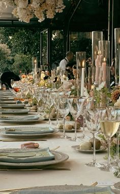 a long table is set with wine glasses and place settings for an elegant dinner party