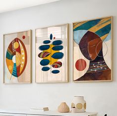 three abstract paintings hang on the wall above a dresser